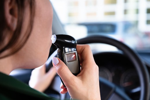 Woman in her vehicle blowing on a ignition interlock device to test her blood alcohol level.