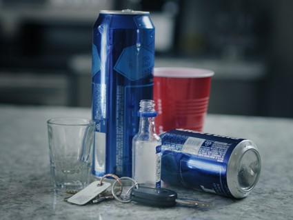 Car keys next to empty booze bottles and a red solo cup symbolizing a possible MIP charge at a party with underage drinking