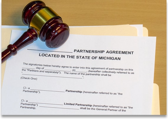 Business attorney document on a desk titled 'Partnership Agreement Located in the State of Michigan.' The document is next to a gavel and yellow folder.